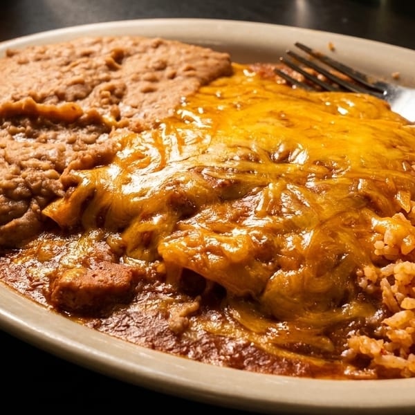 A plate of cheesy enchiladas, refried beans, and Spanish rice with a fork.